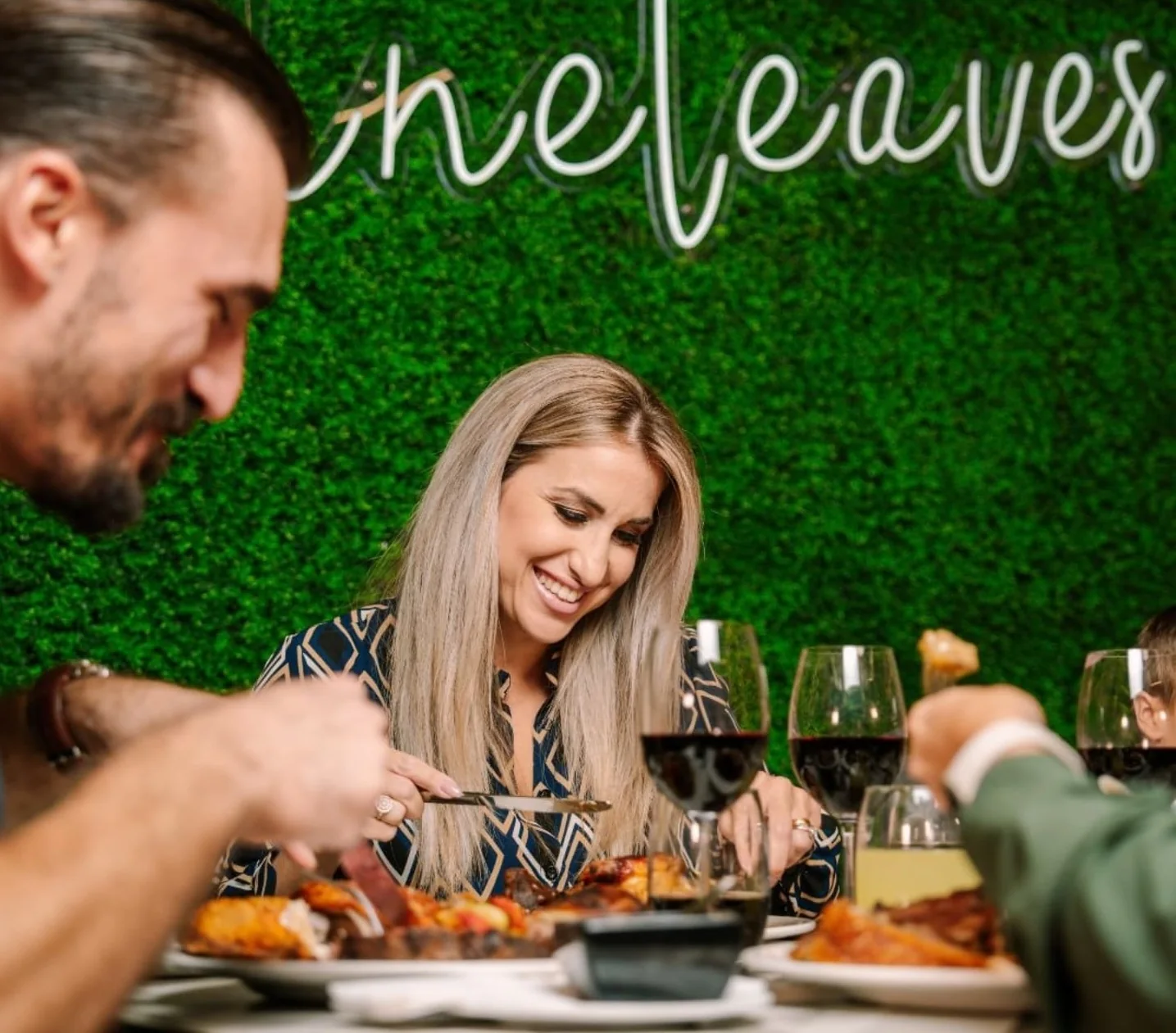 Friends sharing a meal beneath the Vineleaves sign